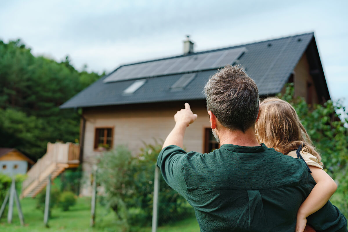 man pointing at solar panels on roof